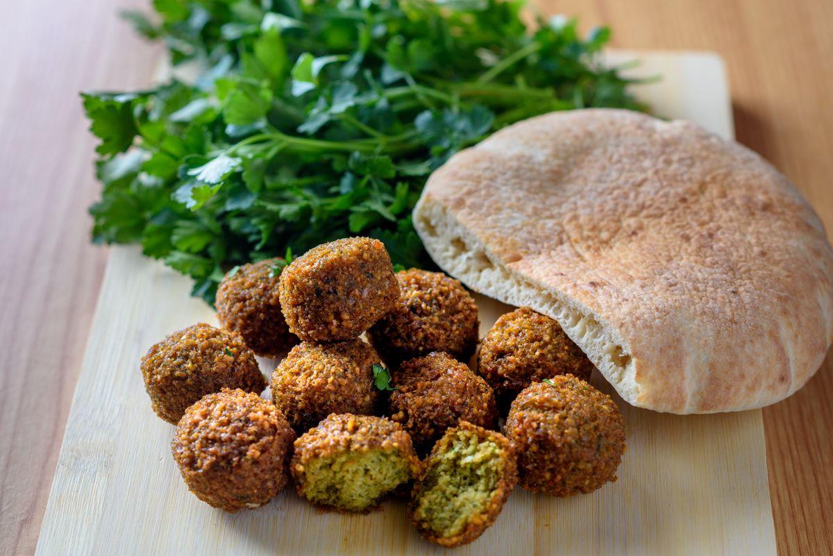 Preparing dishes. Falafel balls, pita and green fresh parsley  on wood rustic background. Falafel is a traditional Middle Eastern food, commonly served in a pitta. 