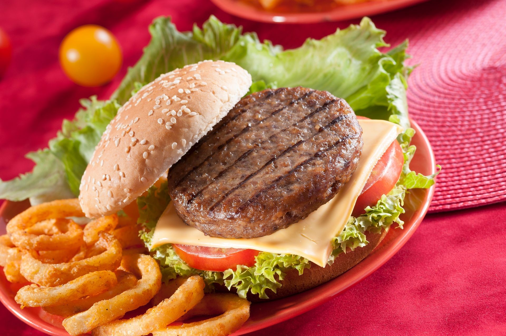 Beef Burger with bell pepper and lettuce with cherry red and yellow tomato on Red background 